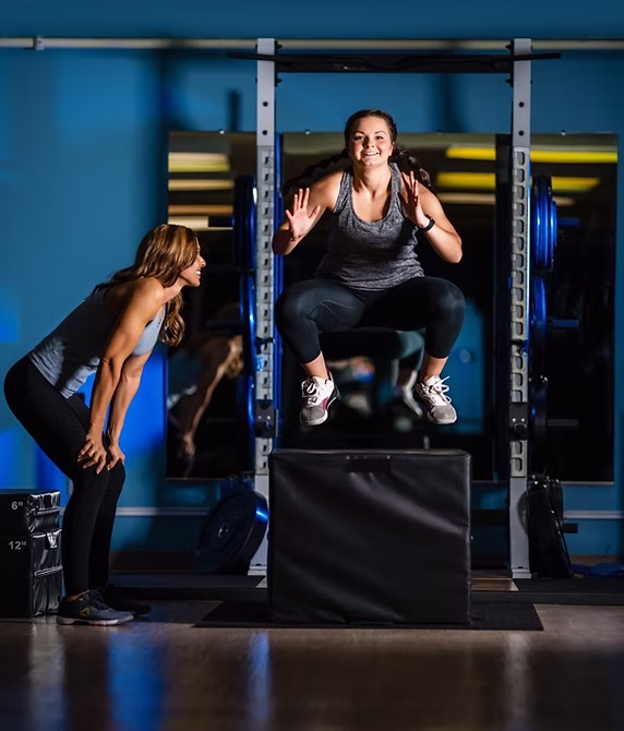 Coach guiding a client through a box jump exercise